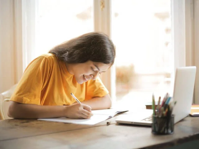 jovem com lap top, pepel e caneta sobre a mesa estudando os melhores metodos de aprender inglês