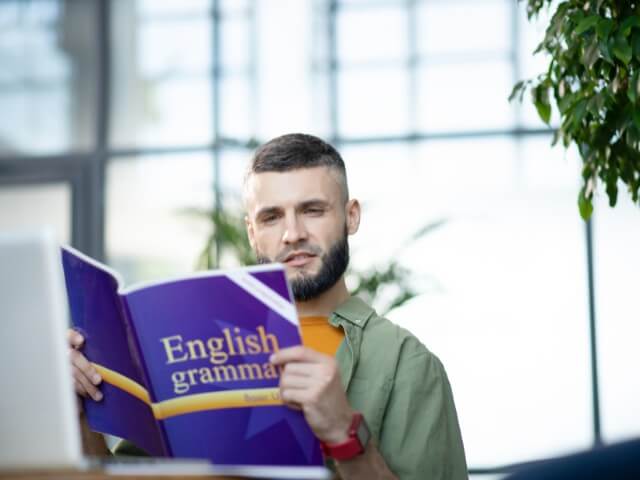 homem lendo livro de gramatica da lingua inglesa